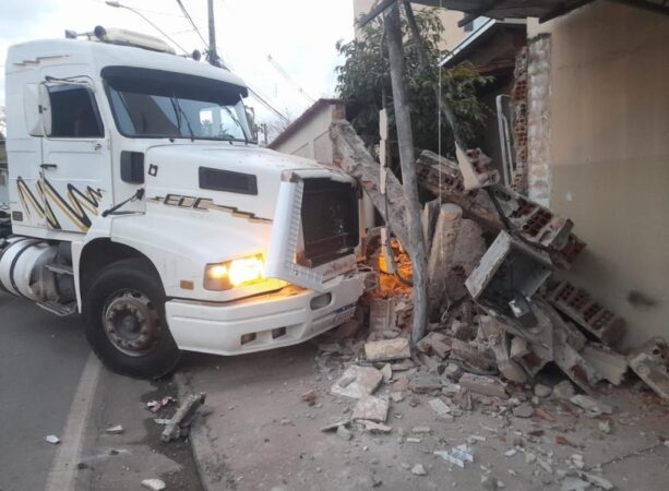 Motorista bate caminhão, destrói muro e telhado de duas casas e foge